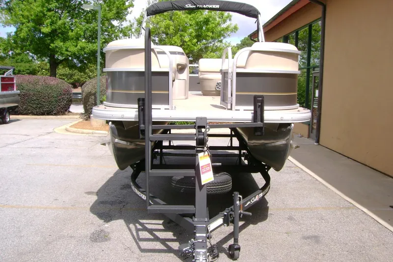 Slide: The Image of 2025 Sun Tracker Party Barge 18 DLX pontoon boat on trailer in parking lot. - 12
