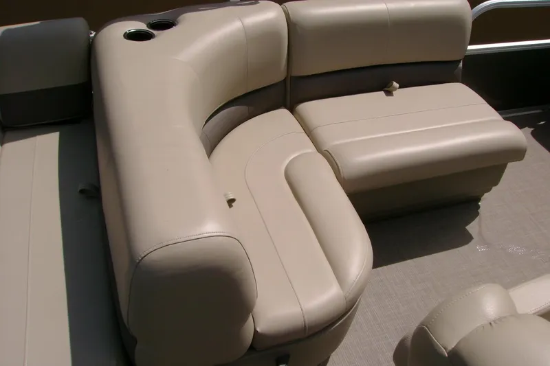 Slide: The Image of 2025 Sun Tracker Party Barge 18 DLX interior seating with beige upholstery and cup holders. - 9