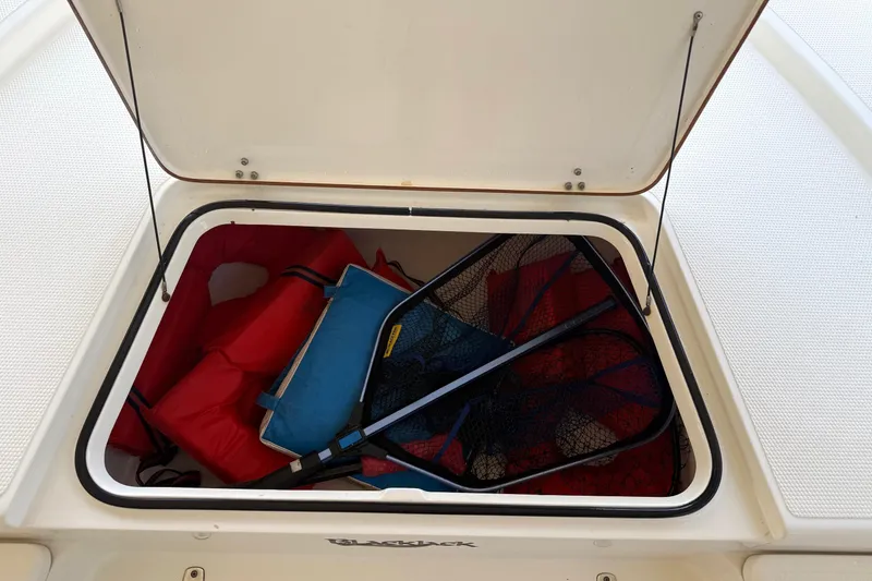 Slide: The Image of Open storage compartment on a 2006 BlackJack 224 boat with fishing gear and life jackets. - 19