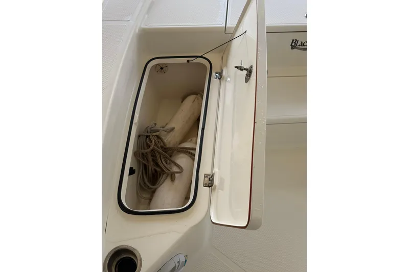 Slide: The Image of Open storage compartment on 2006 BlackJack 224 boat, containing ropes and fenders. - 21