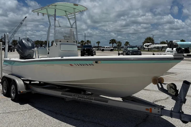 Slide: The Image of 2006 BlackJack 224 boat on trailer, parked in a marina with cloudy sky background. - 4