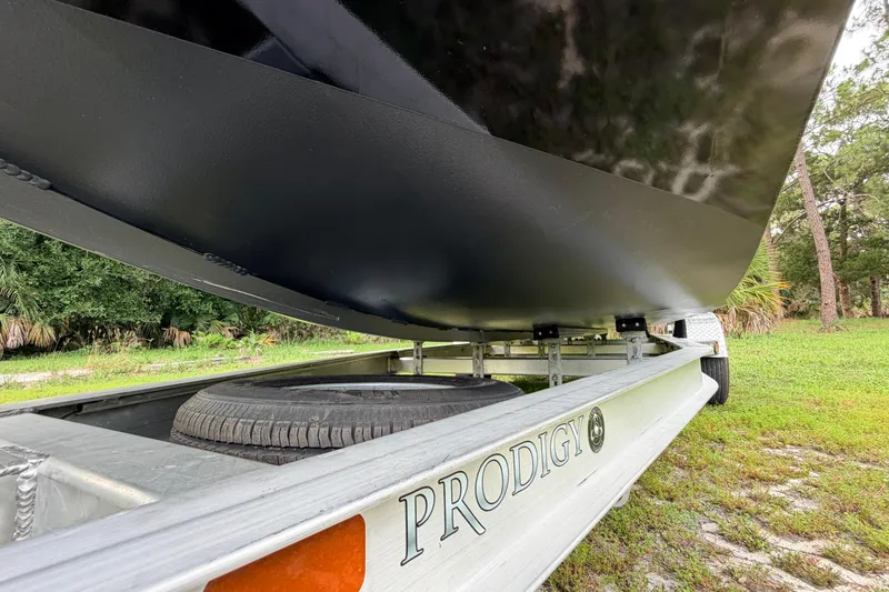 Slide: The Image of Trailer with Prodigy 1854 boat, 2024 model, parked on grassy area. - 11