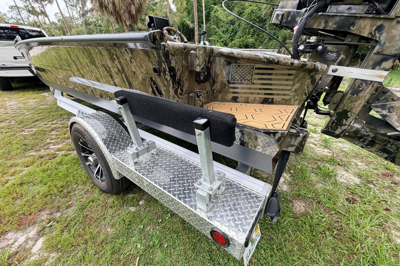 Slide: The Image of 2024 Prodigy 1854 boat on trailer, featuring camouflage design and American flag detail. - 13