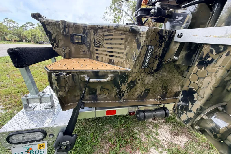 Slide: The Image of Camouflage-patterned Prodigy 1854 boat, 2024 model, on a trailer with American flag design. - 16