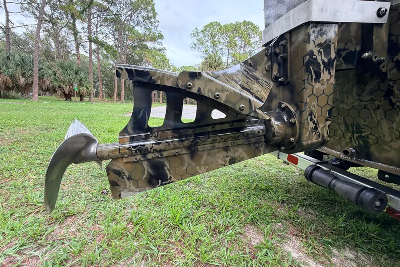 Slide: The Image of Camouflage-patterned Prodigy 1854 boat part, 2024 model, on grassy terrain. - 22