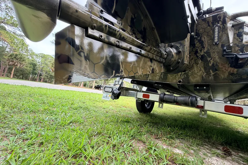 Slide: The Image of 2024 Prodigy 1854 boat with camouflage design on a trailer, parked on grass. - 23