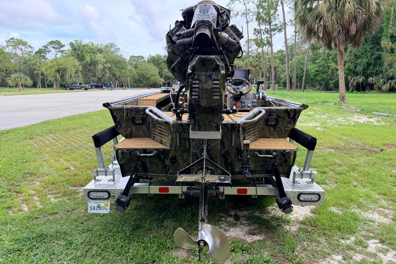 Slide: The Image of 2024 Prodigy 1854 boat on trailer, featuring powerful engine and camo design in a lush park setting. - 3