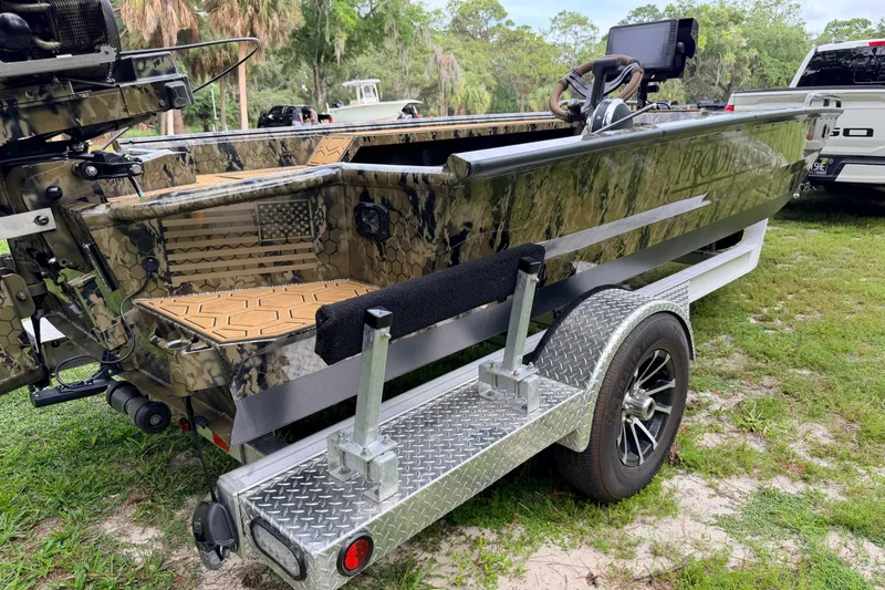 Slide: The Image of 2024 Prodigy 1854 boat on trailer, camo design, parked on grass. - 35