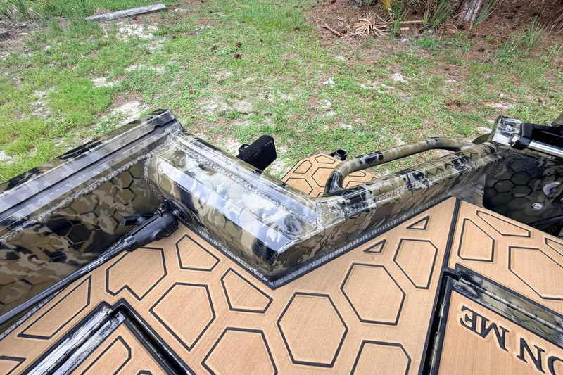 Slide: The Image of 2024 Prodigy 1854 boat with camo design and textured flooring, parked on grass. - 45