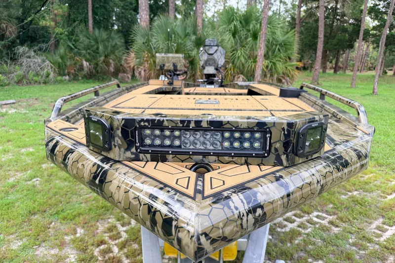 Slide: The Image of 2024 Prodigy 1854 boat with camouflage design and LED lights in a forest setting. - 80