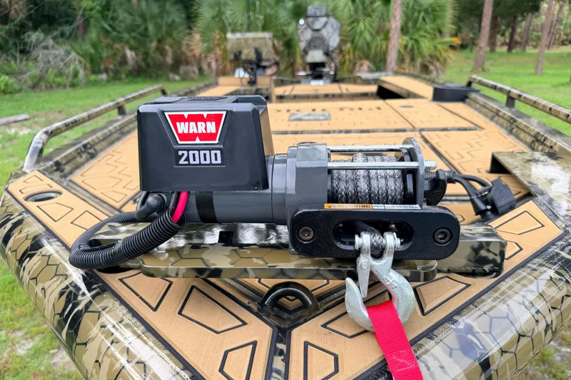 Slide: The Image of 2024 Prodigy 1854 boat with Warn 2000 winch on camouflage deck in a forest setting. - 84