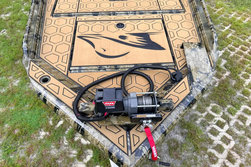 Slide: The Image of 2024 Prodigy 1854 boat with hexagonal deck pattern and mounted winch on grassy terrain. - 85