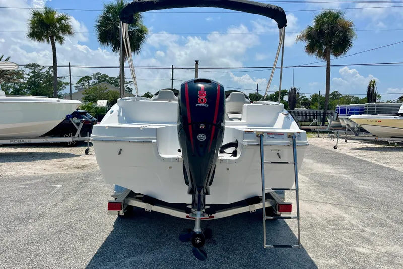 Slide: The Image of 2024 Hurricane Sundeck Sport 218 OB boat with outboard motor and ladder, parked outdoors. - 4