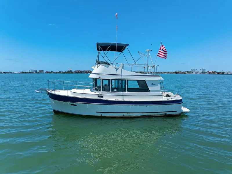 The Image of 2001 Camano 31 Trawler on calm water with blue sky and American flag. - 0