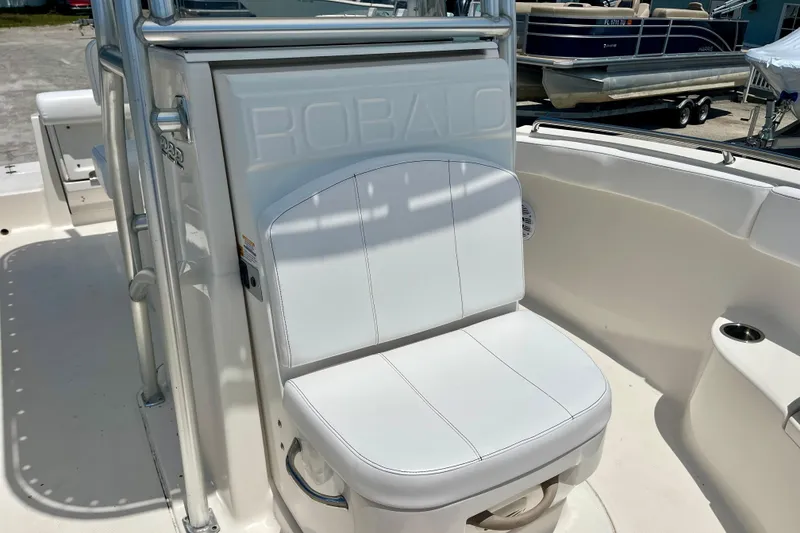 Slide: The Image of 2016 Robalo R222 Center Console boat seat, white upholstery, docked near other boats. - 16