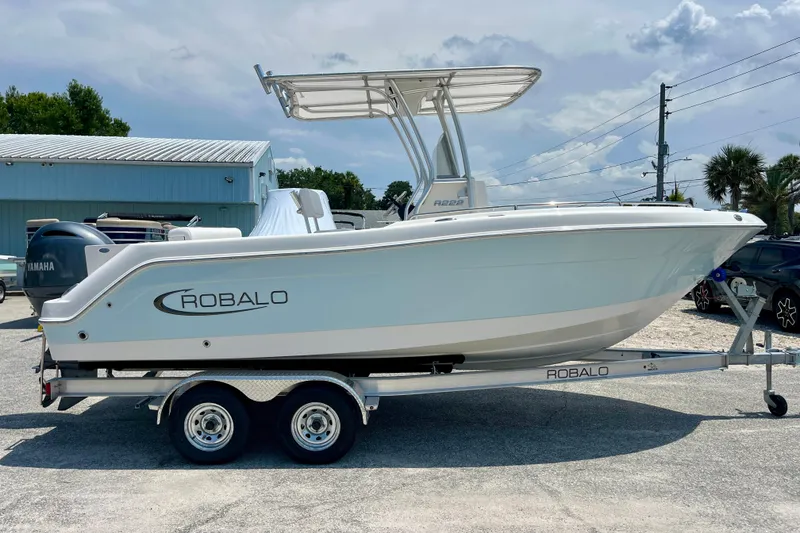 Slide: The Image of 2016 Robalo R222 Center Console boat on trailer, parked outdoors under a cloudy sky. - 6