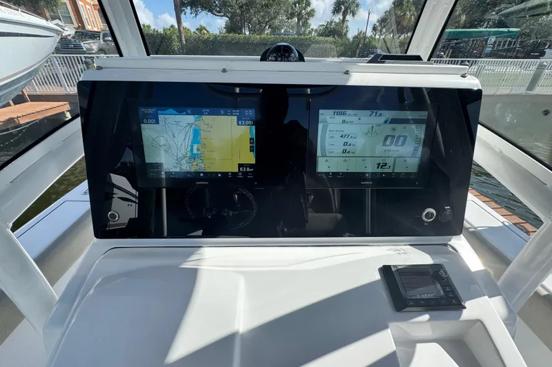 Slide: The Image of 2021 Sportsman Masters 267 Bay Boat dashboard with dual Garmin displays and navigation controls. - 10