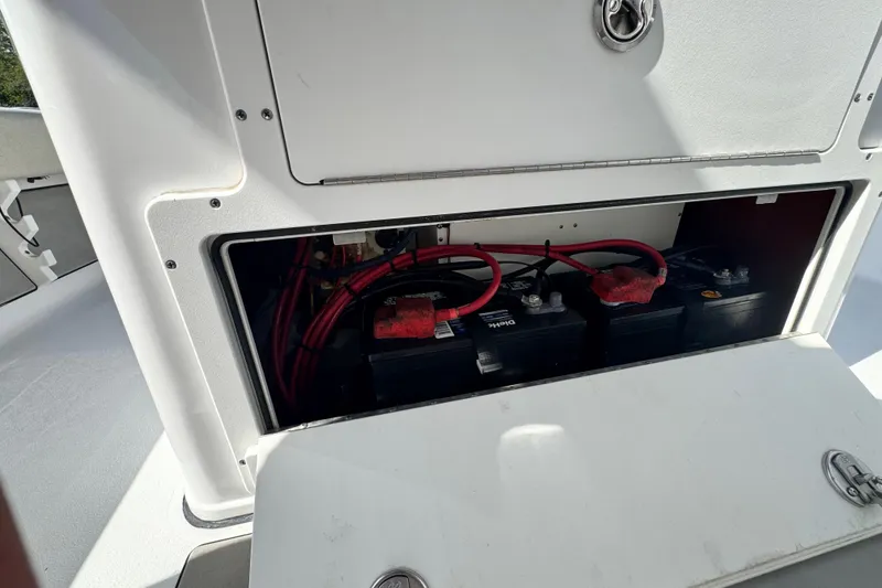 Slide: The Image of 2021 Sportsman Masters 267 Bay Boat battery compartment with red cables and dual batteries. - 18