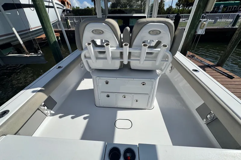 Slide: The Image of 2021 Sportsman Masters 267 Bay Boat interior with seating and storage, docked by the water. - 19
