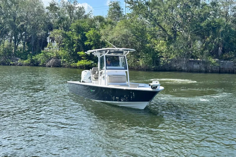 Slide: The Image of 2021 Sportsman Masters 267 Bay Boat cruising on a scenic river with lush greenery. - 4