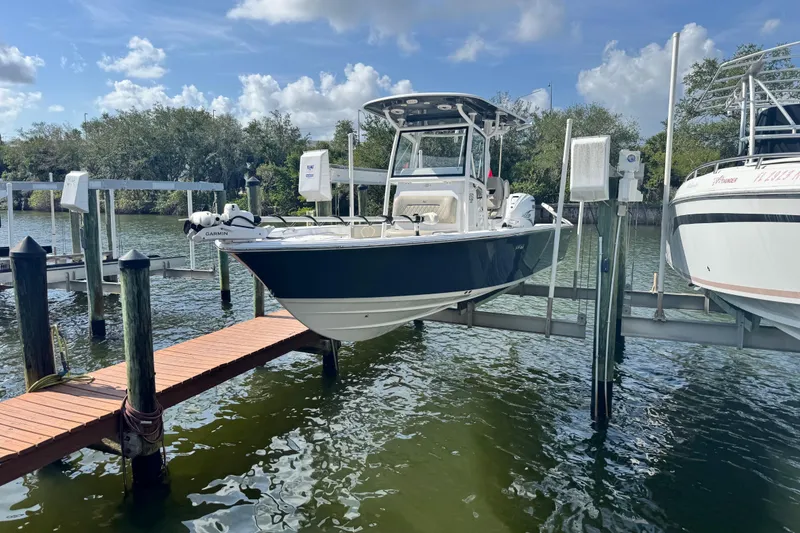 Slide: The Image of 2021 Sportsman Masters 267 Bay Boat docked on a lift, surrounded by water and trees. - 8