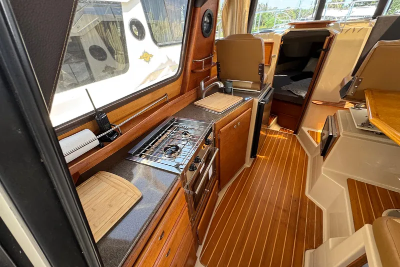Slide: The Image of Interior of 2019 Ranger Tugs R-29 CB, featuring a compact kitchen with wooden flooring. - 19