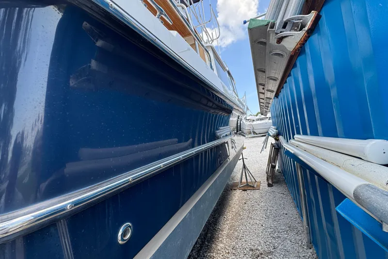 Slide: The Image of 2019 Ranger Tugs R-29 CB boat docked beside a blue structure, gravel ground. - 5