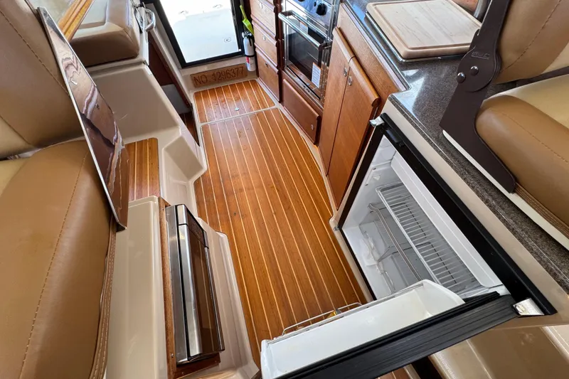 Slide: The Image of 2019 Ranger Tugs R-29 CB interior with wood flooring, open fridge, and seating. - 35