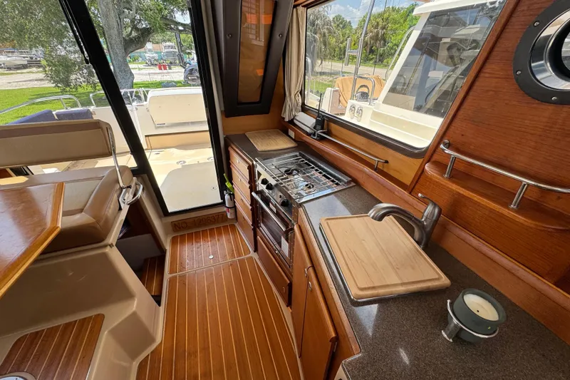 Slide: The Image of Interior of 2019 Ranger Tugs R-29 CB, featuring a compact kitchen with wood accents. - 37
