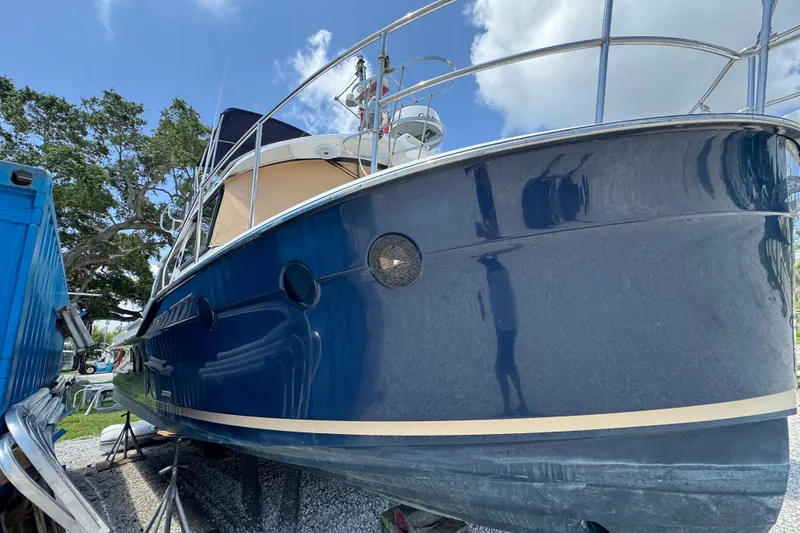 Slide: The Image of 2019 Ranger Tugs R-29 CB boat with blue hull, docked outdoors under a clear sky. - 4