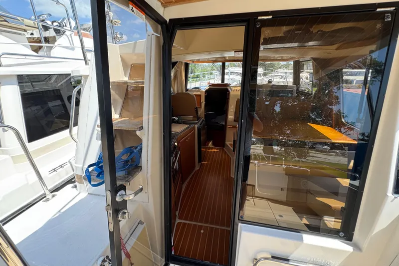Slide: The Image of 2019 Ranger Tugs R-29 CB interior view through open door, showcasing cabin and seating area. - 18