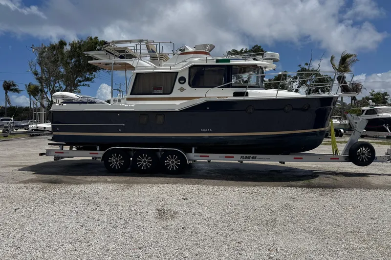 The Image of 2019 Ranger Tugs R-29 CB boat on trailer, parked outdoors under cloudy sky. - 0