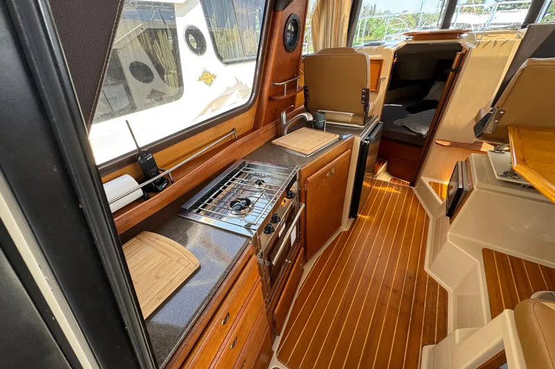 Slide: The Image of Interior of 2019 Ranger Tugs R-29 CB, featuring a compact kitchen with wood accents. - 21