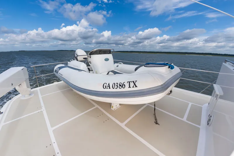 Slide: The Image of A dinghy on a yacht deck, surrounded by water and a cloudy sky. - 25