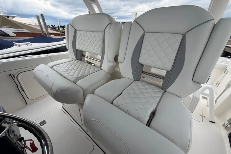 Slide: The Image of 2024 Pursuit S 328 Sport boat seats with quilted upholstery, docked at marina. - 13