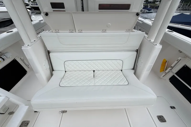 Slide: The Image of 2024 Pursuit S 328 Sport boat interior with white cushioned seating and storage compartments. - 15