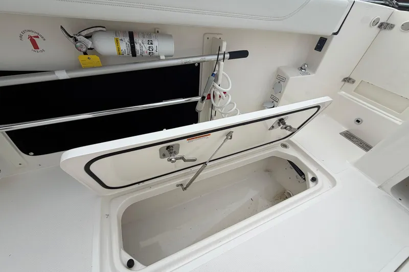 Slide: The Image of 2024 Pursuit S 328 Sport boat storage compartment with fire extinguisher and hose. - 30
