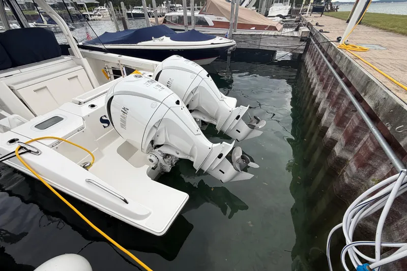 Slide: The Image of 2024 Pursuit S 328 Sport boat with dual outboard engines docked at marina. - 33