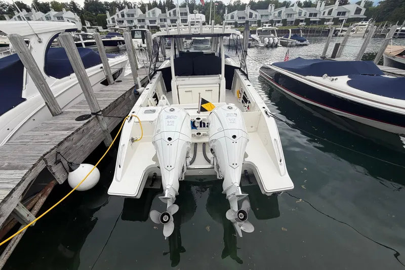 Slide: The Image of 2024 Pursuit S 328 Sport boat docked with twin outboard engines in a marina. - 34