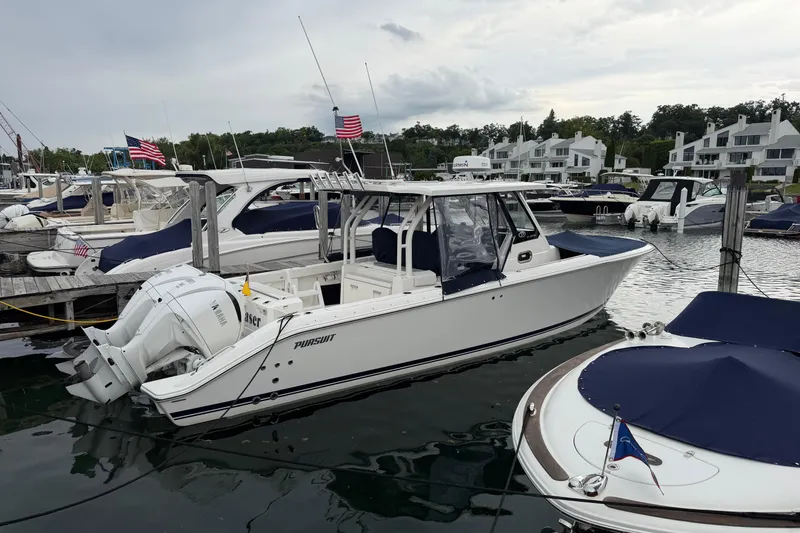 Slide: The Image of 2024 Pursuit S 328 Sport boat docked in a marina with other vessels. - 35