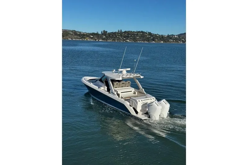 The Image of 2024 Tiara Sport 34LS boat cruising on a serene lake with scenic background. - 0