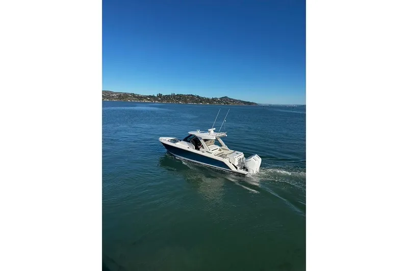 Slide: The Image of 2024 Tiara Sport 34LS boat cruising on a clear blue sea under a sunny sky. - 28