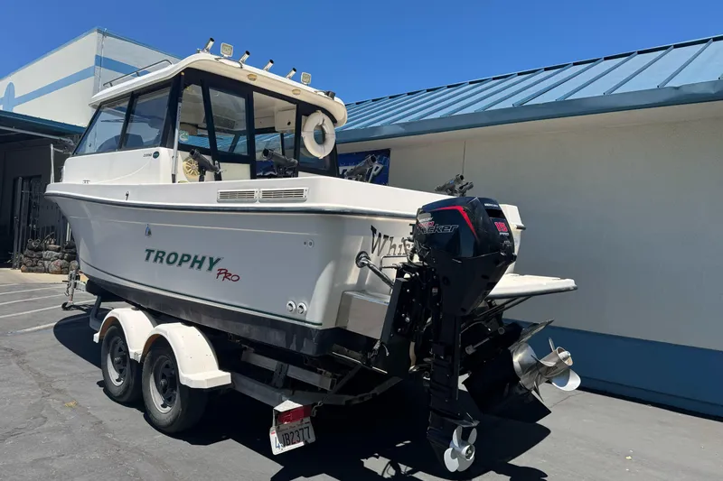 Slide: The Image of 2004 Trophy 2359 WA boat on trailer, parked outdoors, featuring Mercury outboard motor. - 8