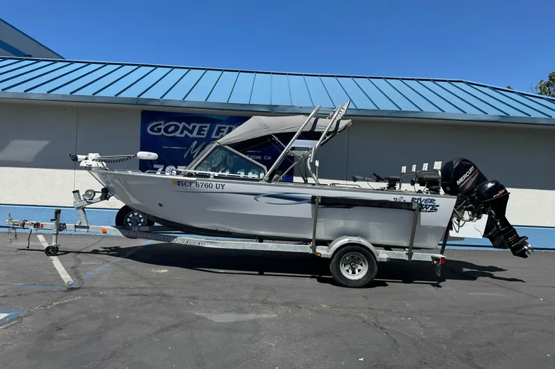 Slide: The Image of 2014 River Hawk 19 GB boat on trailer, parked outside a building. - 1