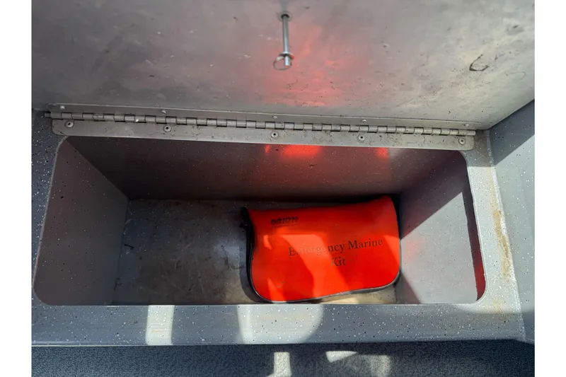 Slide: The Image of Open storage compartment with an emergency marine kit inside a 2014 River Hawk 19 GB boat. - 23