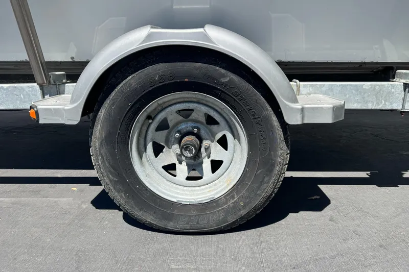 Slide: The Image of Trailer wheel of a 2014 River Hawk 19 GB boat, parked on pavement. - 29