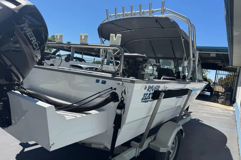 Slide: The Image of 2014 River Hawk 19 GB boat with Mercury engine on trailer, parked outdoors. - 5