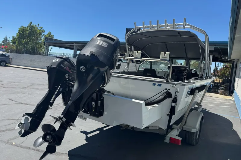 Slide: The Image of 2014 River Hawk 19 GB boat with dual outboard motors in a parking lot. - 6