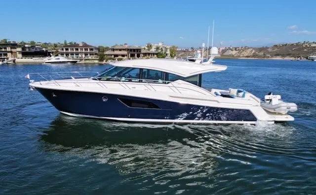 The Image of A sleek 2017 Tiara Yachts C53 Coupe cruising on calm waters, surrounded by coastal homes. - 0