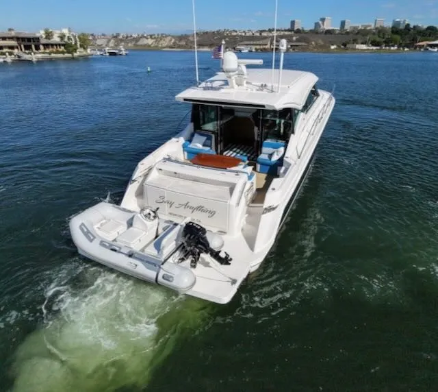 Slide: The Image of A 2017 Tiara Yachts C53 Coupe cruising on calm waters with a dinghy attached at the stern. - 4